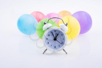 Alarm clock and colorful small balloons on a white background