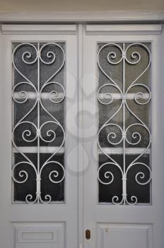 White wooden door frame with glass lite and vintage metal pattern.