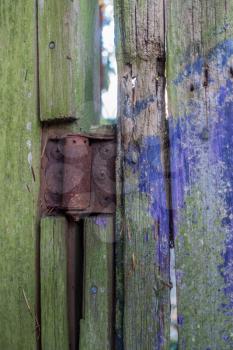 A rusted hinge holds up a cedar gate. Macro shot.