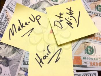 American cash money and yellow sticky note with text Make-up and hair and date night in black color aerial view