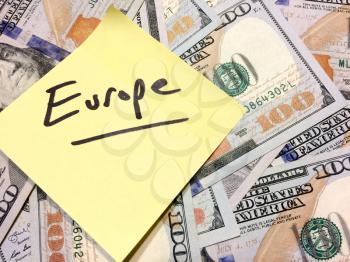 American cash money and yellow sticky note with text Europe in black color aerial view