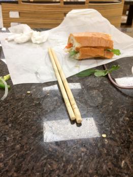 Finished half eaten sandwich meal at reataurant on white paper chopsticks