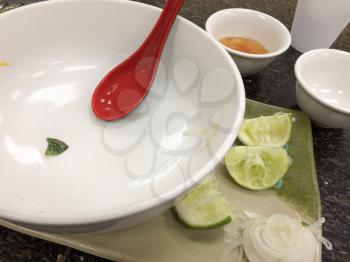 Empty white bowl after finished meal with red spoon at restaurant