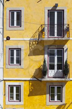 Bright yellow facade  with square symmetrical windows in Lisbon, Portugal