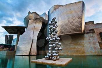 Guggenheim Museum of contemporary Art reflected in the water and the work Tall Tree and The Eye in Bilbao, Spain.