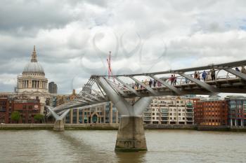 LONDON, UK - JUNE 5 , 2017:  Tourists walking across the Millennium bridge to St. Paul Cathedral by a cloudy day in London
