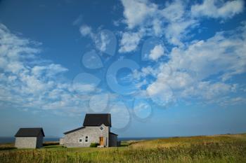 Grey house in a middle of a field in Magdalen island in Canada.  Image taken from the street.