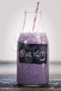 Blueberry smoothie in a bottle with a straw