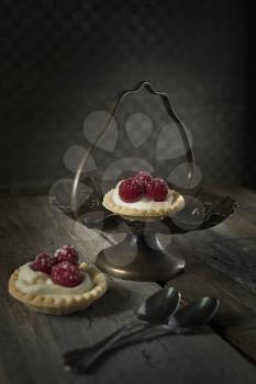 Raspberry tarts with spoons in a stand with a rustic style