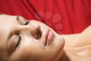 Royalty Free Photo of a Beautiful Young Female Lying on a Red Background With Eyes Closed