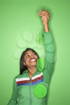 Royalty Free Photo of a Smiling Woman Wearing a Green Coat Standing In Front of a Green Background Holding a Green Mobile
