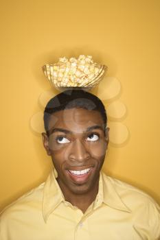 Royalty Free Photo of a Man Balancing a Bowl of Popcorn on His Head