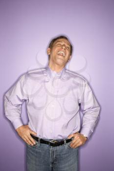 Royalty Free Photo of a Laughing Middle-Aged Man Wearing Purple Clothing on a Purple Background