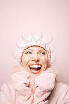 Royalty Free Photo of a Smiling Woman on a Pink Background Wearing a Winter Coat and Hat