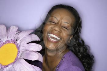 Royalty Free Photo of a Woman Holding a Large Fake Flower and Laughing