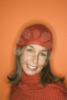 Royalty Free Photo of a Woman on an Orange Background Wearing a Winter Hat and Scarf