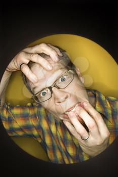 Royalty Free Photo of a Vignette of a Man on a Yellow Background Pulling at Face and Looking Stressed