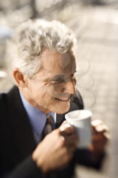 Royalty Free Photo of a Selective Focus of a Man in a Suit Drinking Coffee and Smiling