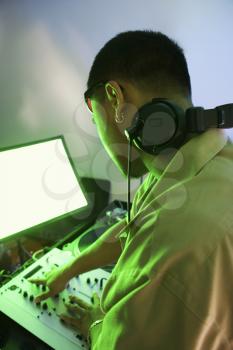 Royalty Free Photo of a Rear view of an Asian Male DJ Mixing Music on Equipment