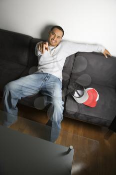 Royalty Free Photo of a Young Man Sitting on a Sofa Smiling and Pointing