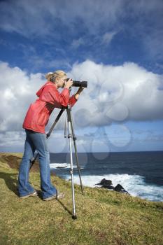 Royalty Free Photo of a Woman Holding a Camera on a Cliff Overlooking the Ocean in Maui, Hawaii