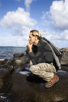 Royalty Free Photo of a Man Kneeling on a Rocky Coast Looking at the Ocean in Maui, Hawaii
