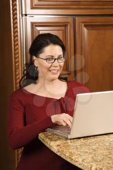 Royalty Free Photo of a Woman Typing on a Laptop in the Kitchen