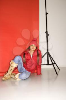 Portrait of Asian-American teen girl in studio setting sitting on floor next to light stand.