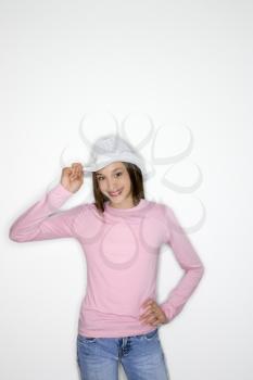 Portrait of Asian-American teen girl tipping cowboy hat and hand on hip standing against white background.