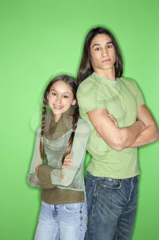 Royalty Free Photo of a Portrait of Asian-American Girl and Teen Boy Standing back to Back Against a Green Background