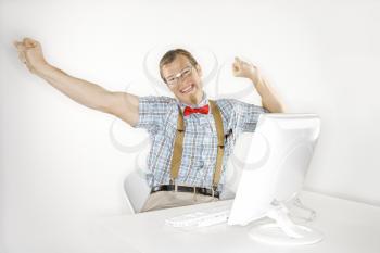Royalty Free Photo of a Young Man Smiling and Stretching Arms Out at a Computer