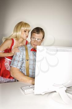Royalty Free Photo of a Blonde Woman Dressed in a French Maid Outfit Whispering to a Man Sitting at a Computer Dressed Like a Nerd