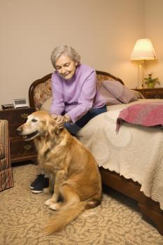 Royalty Free Photo of an Elderly Woman and Dog in a Bedroom at an Retirement Community Center