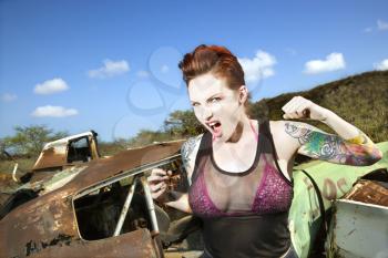 Royalty Free Photo of a Woman Hold Up a Fist in a Junkyard