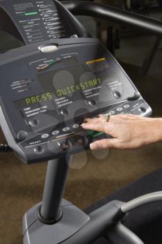 Royalty Free Photo of a Woman Setting up an Elliptical Machine at a Gym