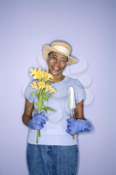 Royalty Free Photo of an Older Woman Holding a Shovel and Flowers