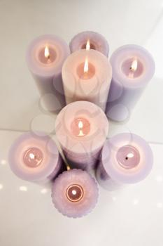 Royalty Free Photo of an Overview of Purple Burning Candles in Front of a Mirror