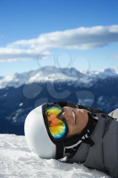 Royalty Free Photo of a Teenage Snowboarder Smiling, Lying in the Snow on Mountain