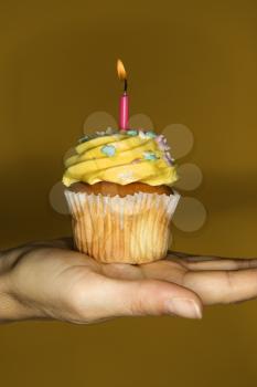 Royalty Free Photo of Female Hand Holding a Cupcake With a Lit Candle