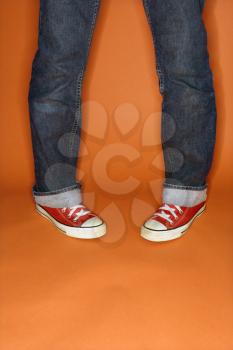 Royalty Free Photo of a Person in Jeans and Sneakers With Feet Turned Inward