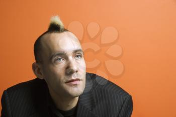 Royalty Free Photo of a Man in a Suit With a Mohawk Against an Orange Background