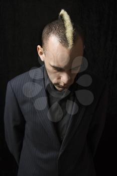 Royalty Free Photo of a Man in a Suit With Mohawk Looking Down Against a Black Background