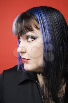 Royalty Free Photo of a Woman With Blue Hair, Tattoos, and a Spike Collar Against an Orange Background