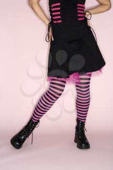 Royalty Free Photo of a Woman Wearing Striped Leggings Against a Pink Background