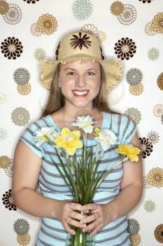 Royalty Free Photo of a Woman Wearing a Straw Hat Holding a Flower Bouquet