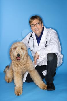 Middle-aged Caucasian male veterinarian with Goldendoodle dog.