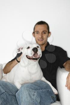 Royalty Free Photo of a Young Man Holding a White Pit Bull Dog on His Lap