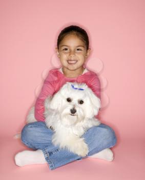 Royalty Free Photo of a Female Hispanic Girl Holding a Maltese Dog