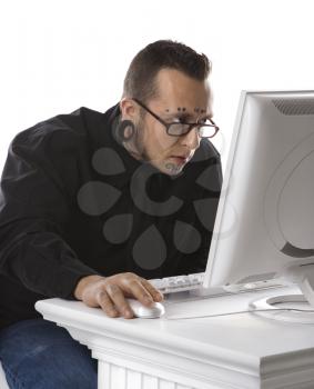 Caucasian mid-adult man  with tattoos and piercings using computer.