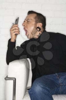 Royalty Free Photo of a Tattooed Man Yelling into a Cellphone